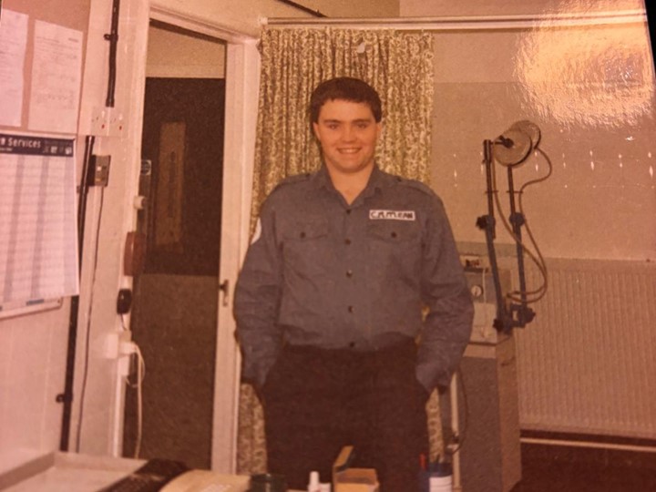 Calum stands smiling in his old navy uniform