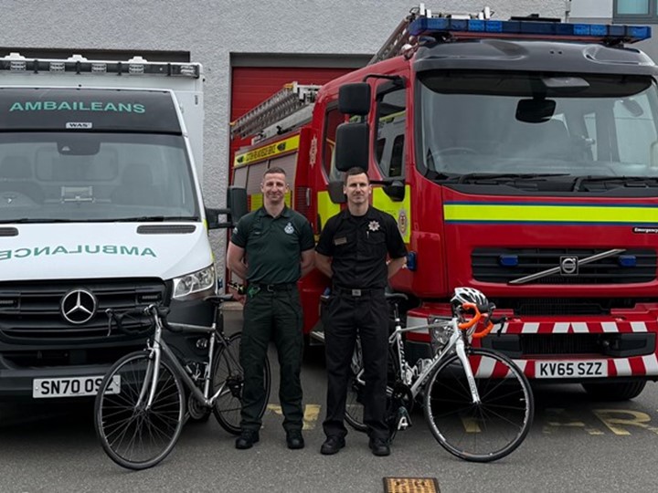 Paramedic Christopher and his firefighter brother John stand proudly in front of an ambulance and fire truck with bikes near them