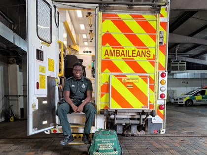 An Ambulance Technician sits on the steps at the back of an A&E ambulance